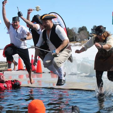 4 men dressed as pirates jump into a hole in the frozen lake
